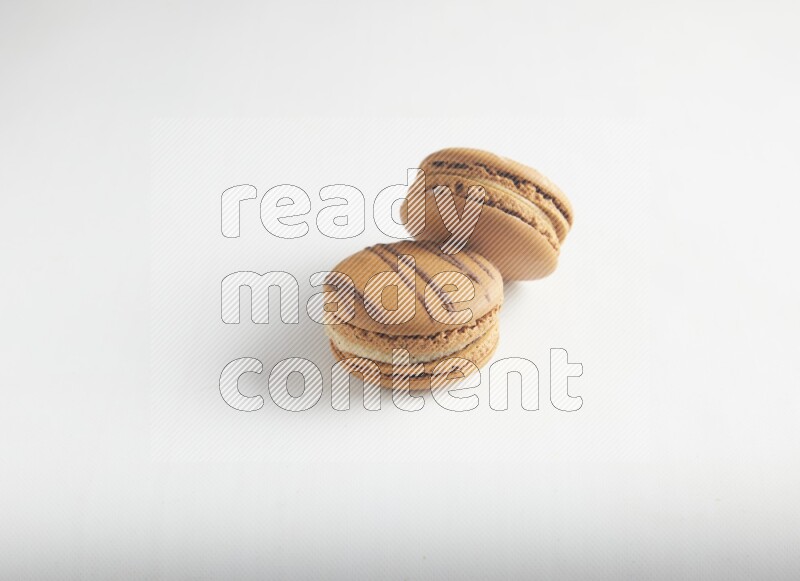 45º Shot of of two assorted Brown Irish Cream, and light brown  Almond Cream macarons on white background