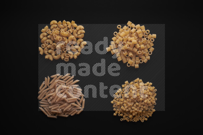 Different pasta types in bunches on black background