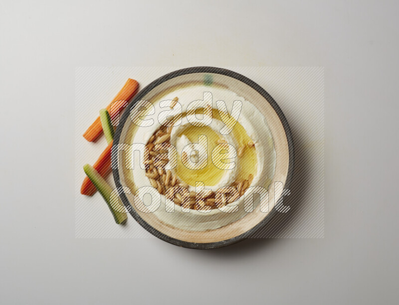 Lebnah garnished with pine nuts in a pottery plate on a white background