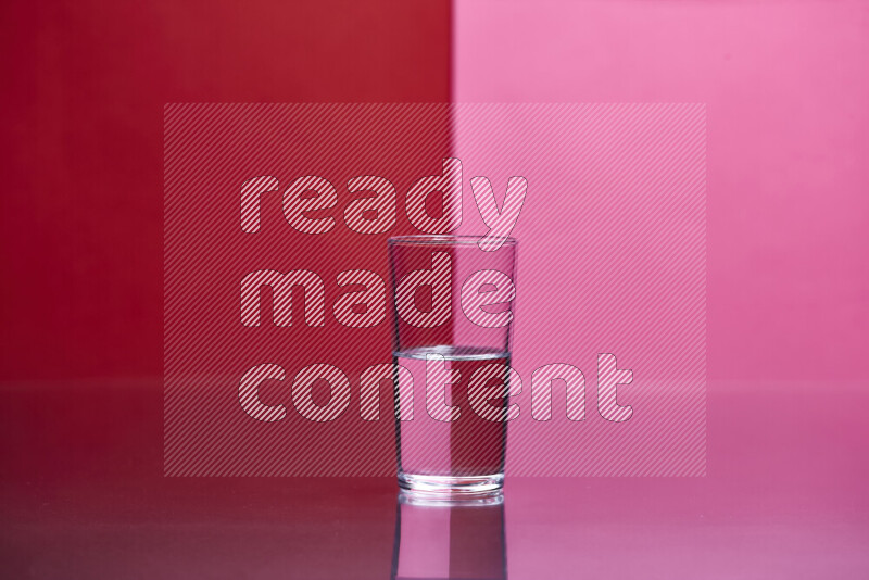 The image features a clear glassware filled with water, set against red and pink background