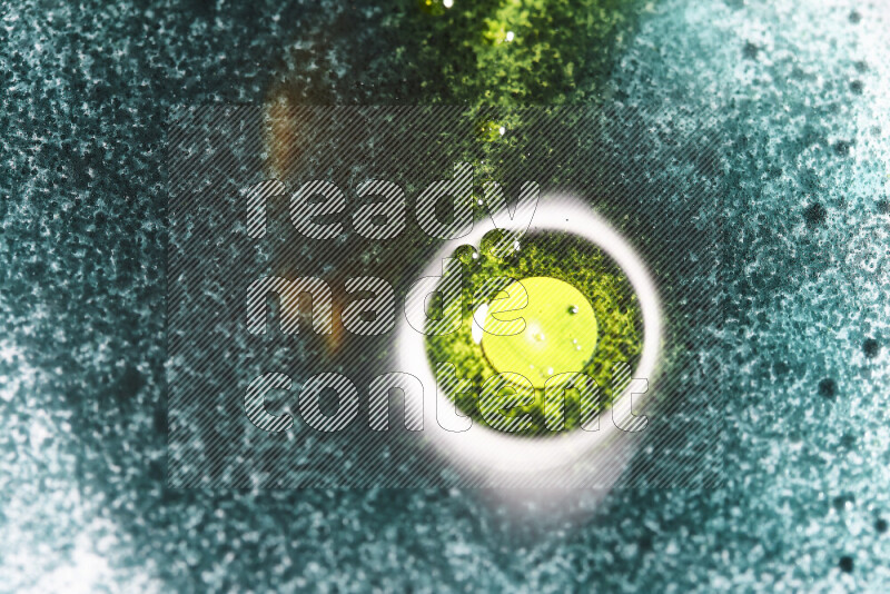 لقطات مقربة لقطرات ألوان مائية خضراء وصفراء على سطح الزيت على خلفية بيضاء