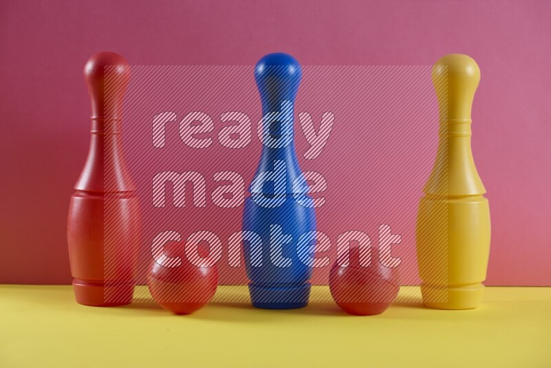 Plastic bowling pins with balls on pink and yellow background (kids toys)