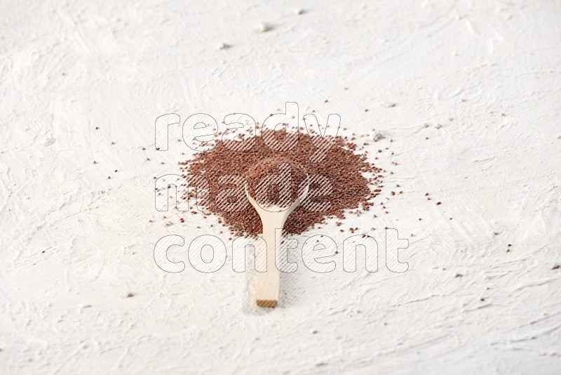 A wooden spoon full of garden cress seeds on a textured white flooring
