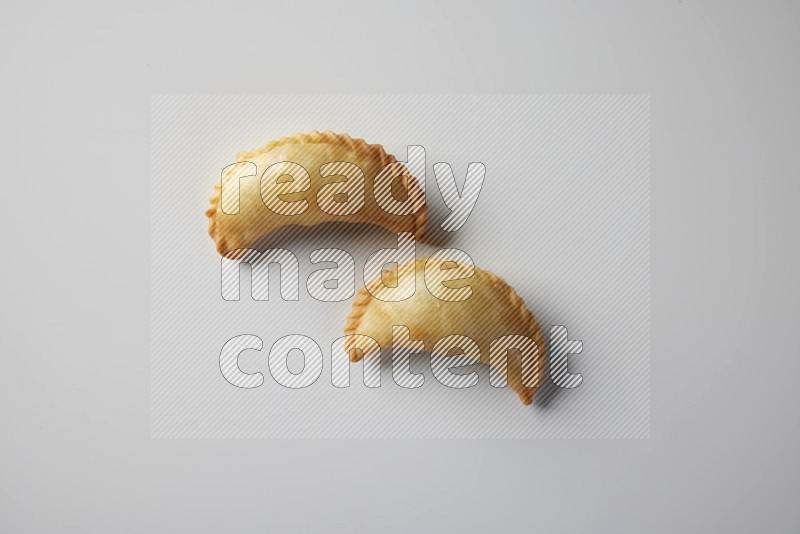 Two fried sambosa from a top angle on a white background