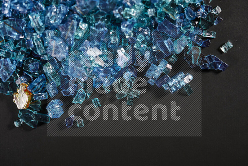Transparent blue fragments of glass scattered on a black background