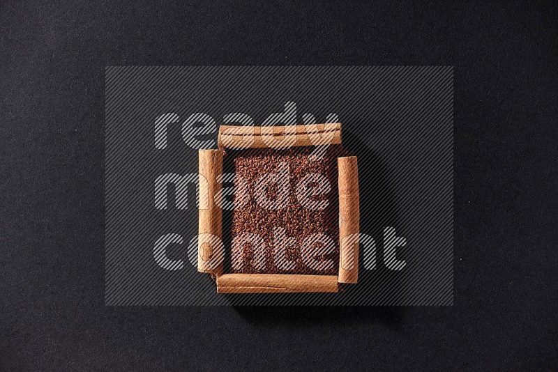 A single square of cinnamon sticks full of garden cress on black flooring