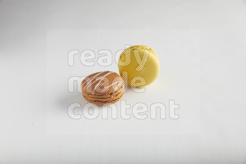 45º Shot of of two assorted Brown Irish Cream, and Yellow Lemon macarons on white background