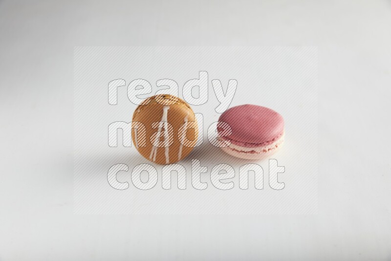 45º Shot of of two assorted Brown Irish Cream, and Pink Litchi Raspberry macarons on white background