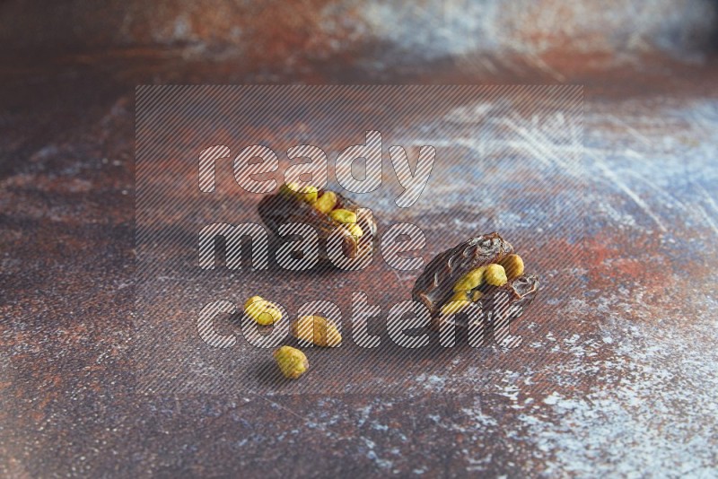 two pistachio stuffed madjoul dates on a rustic reddish background