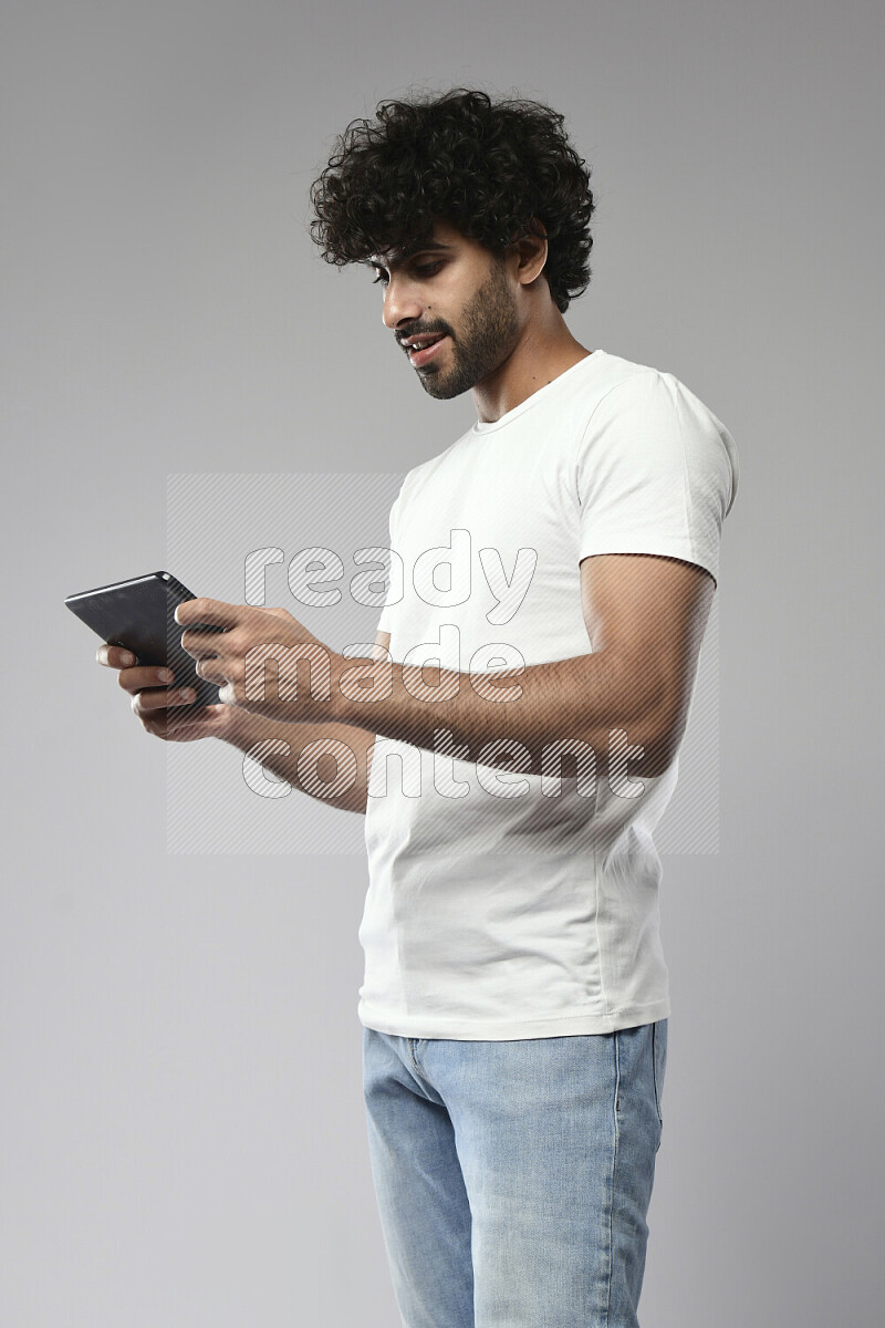 A man wearing casual standing and gaming on a tablet on white background