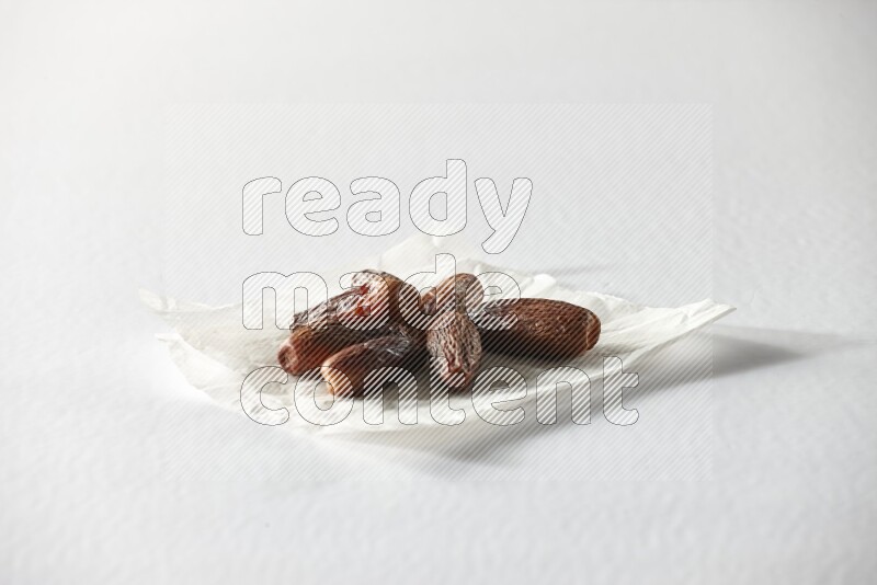 Dried dates on a crumpled piece of paper on a white background in different angles