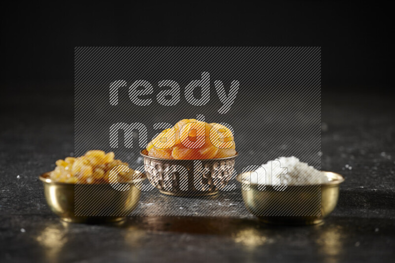 فواكه مجففة في أطباق معدنية علي خلفية سوداء خشبية