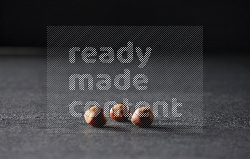 3 hazelnuts on a black background in different angles