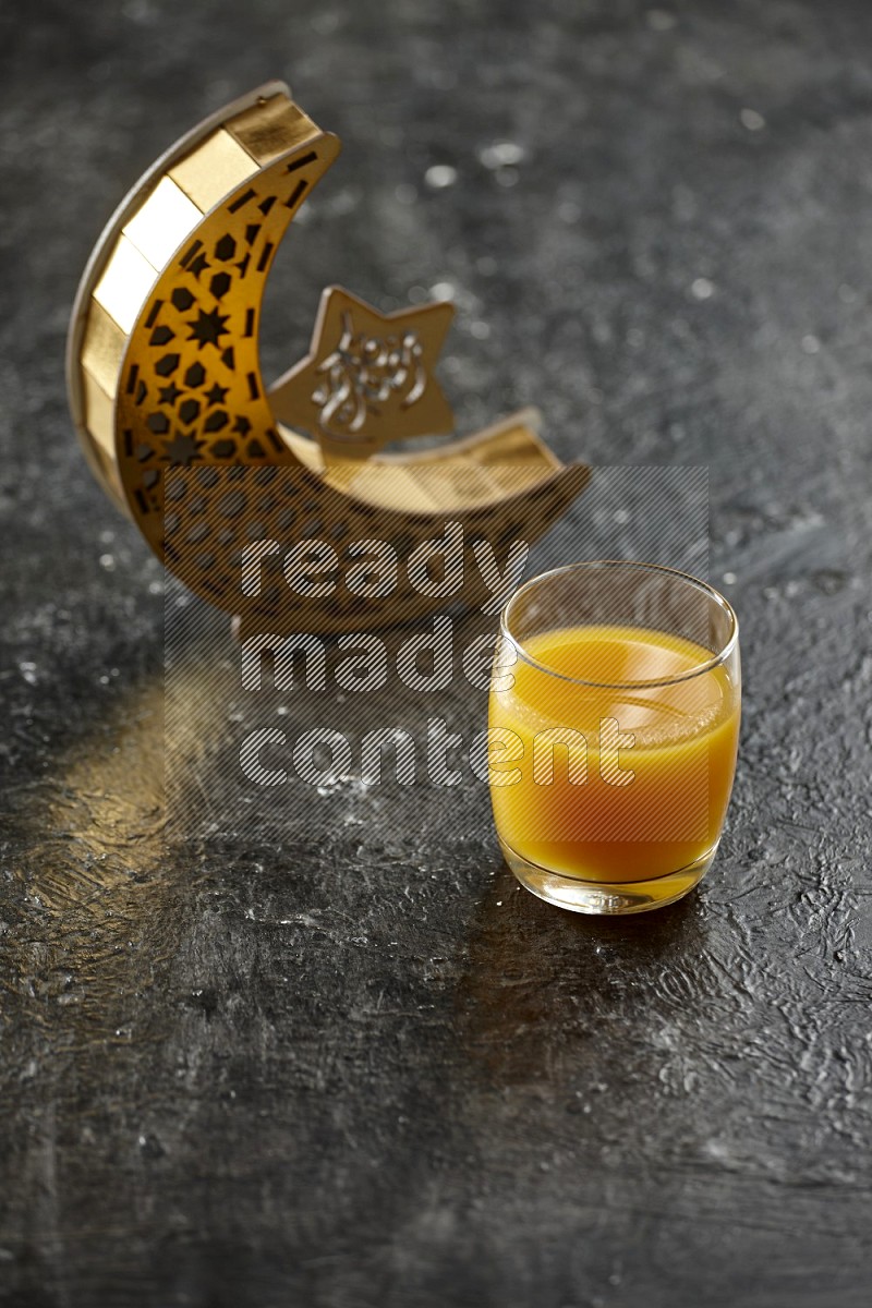 A crescent lantern with drinks, dates, nuts, prayer beads and quran on textured black background