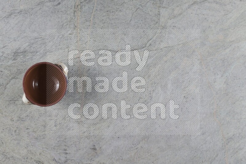 إناء فخاري متعدد الألوان مع غطائه على خلفية من الرخام الرمادي