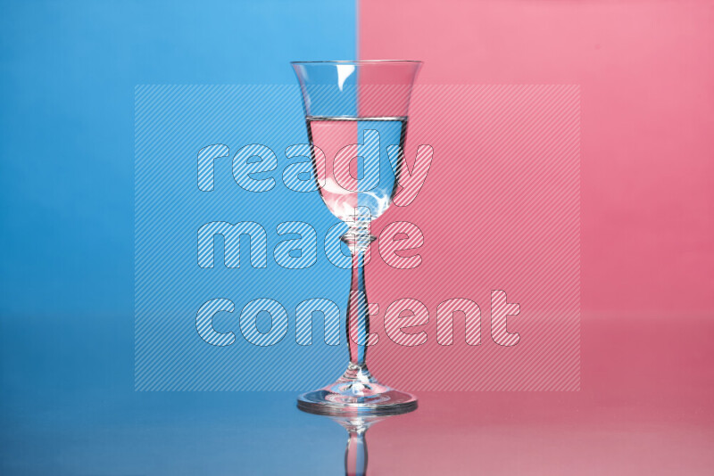 The image features a clear glassware filled with water, set against blue and pink background