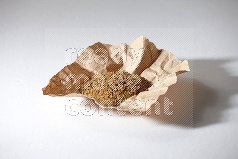 Cumin powder in a crumpled piece of paper on white flooring