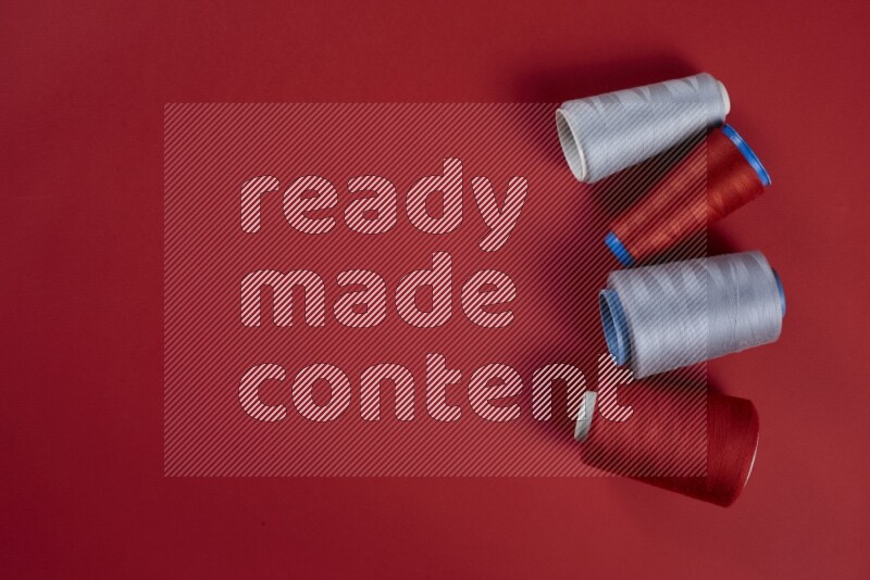 مجموعة من أدوات الخياطة والتفصيل رمادية اللون على خلفية حمراء