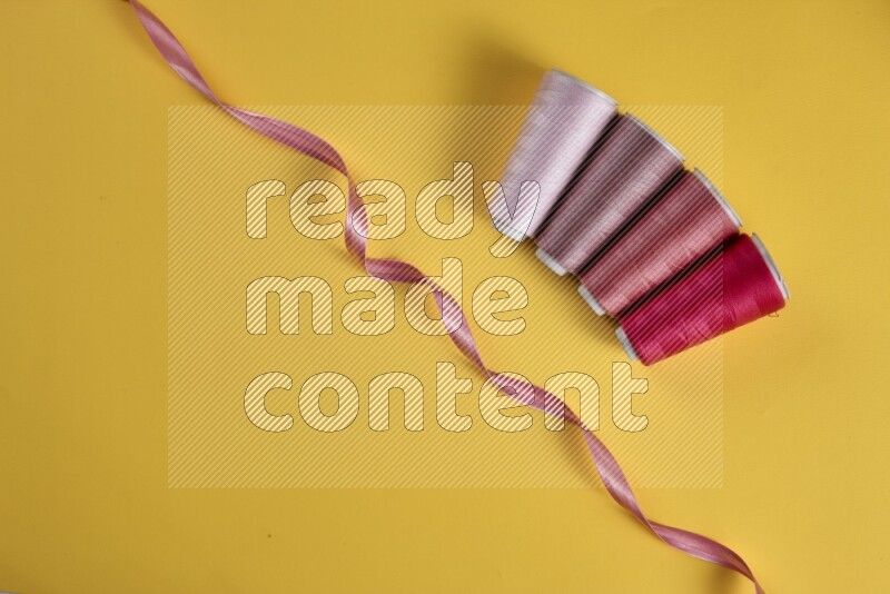 A pink collection of sewing and tailoring tools arranged on a yellow background