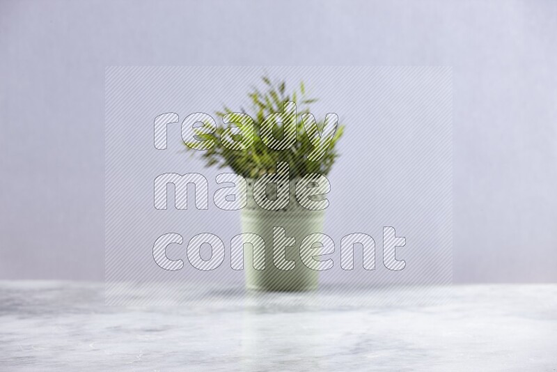 Artificial plant in green decorative pot on grey marble background