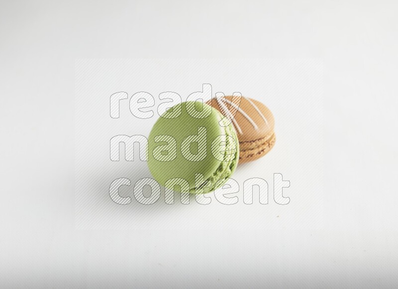 45º Shot of of two assorted Brown Irish Cream, and Green Pistachio macarons on white background