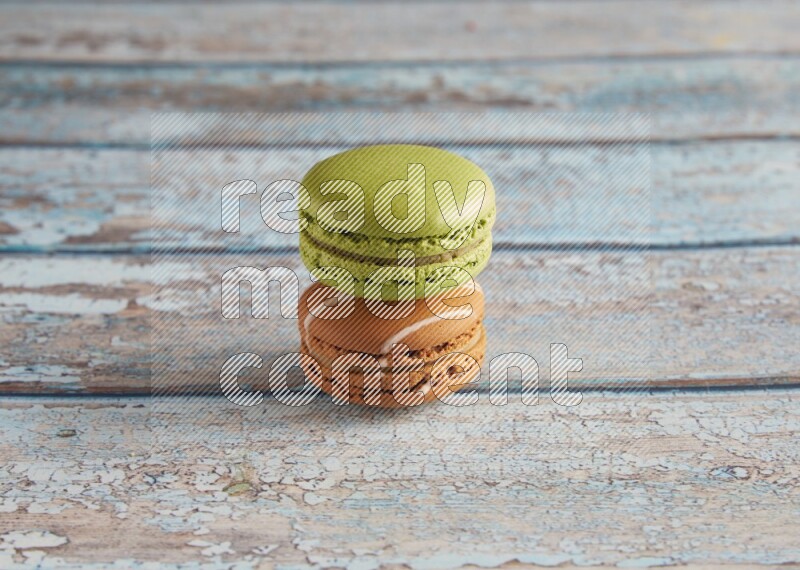 45º Shot of of two assorted Brown Irish Cream, and Green Pistachio macarons  on light blue background