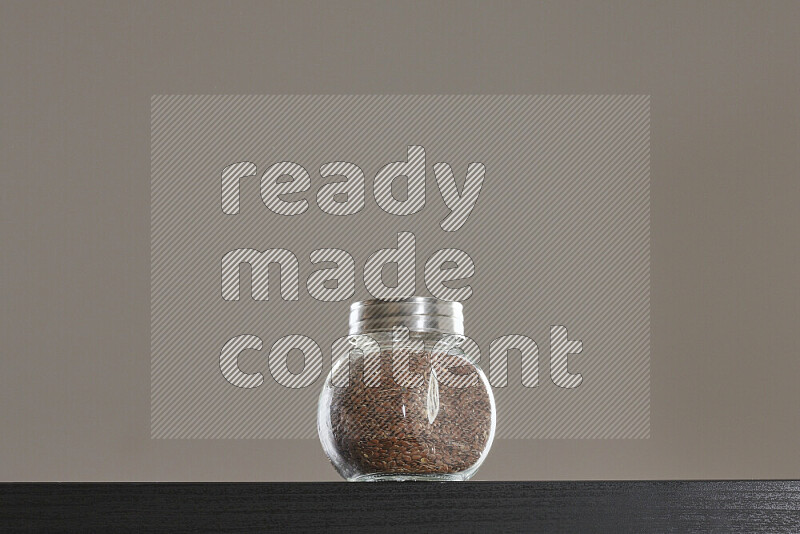 Flax seeds in a glass jar on black background