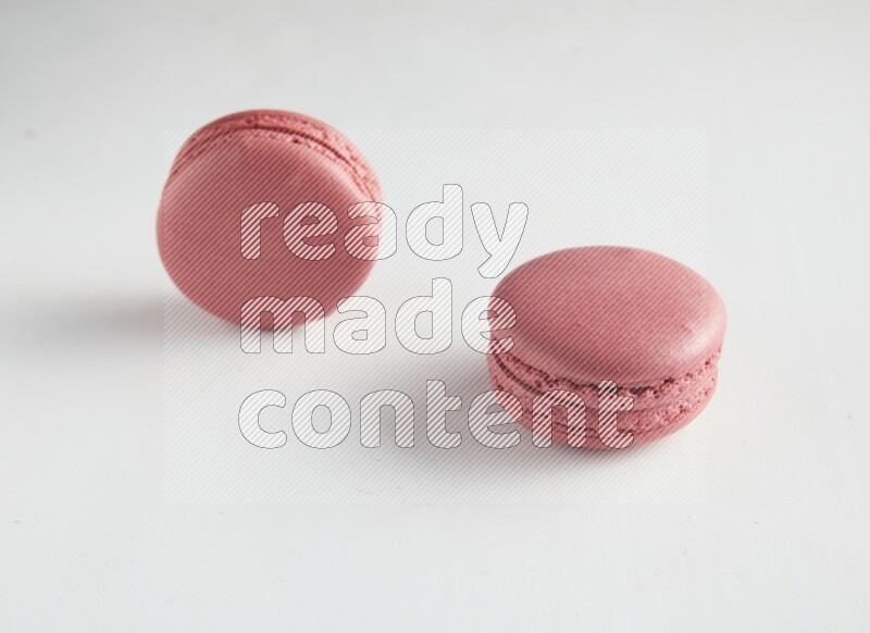45º Shot of two Pink Raspberry macarons on white background