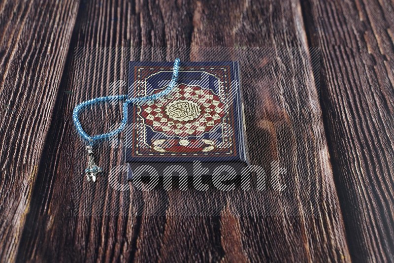 Quran with a prayer beads on wooden background