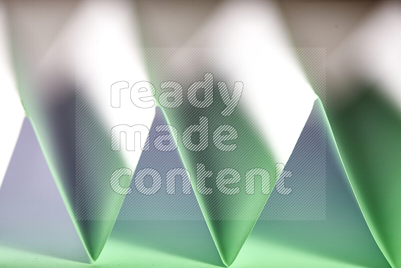 A close-up abstract image showing sharp geometric paper folds in white and green gradients