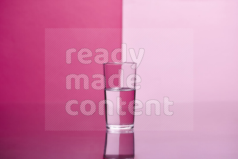 The image features a clear glassware filled with water, set against pink background