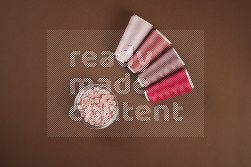 مجموعة من أدوات الخياطة والتفصيل زهرية اللون على خلفية بنية