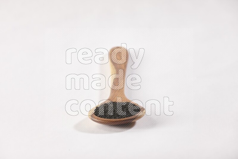 A wooden ladle full of black seeds on a white flooring