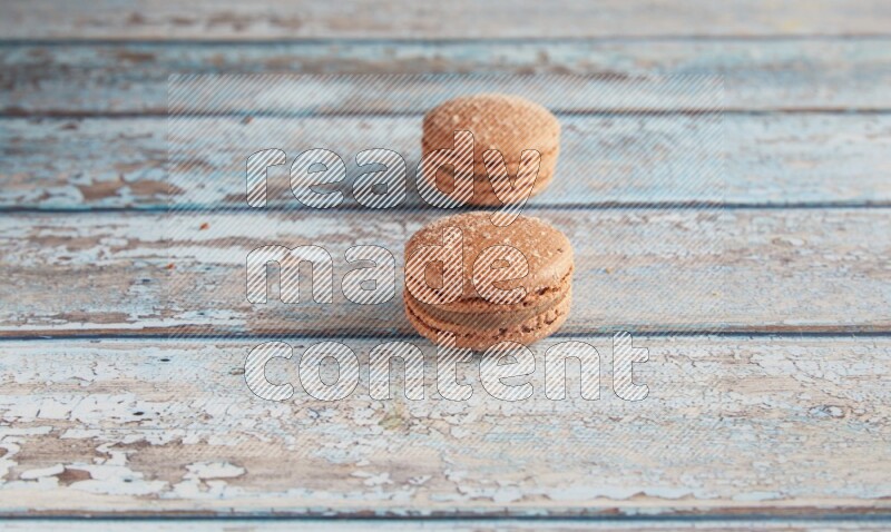 45º Shot of two Brown Hazelnuts macarons on light blue wooden background
