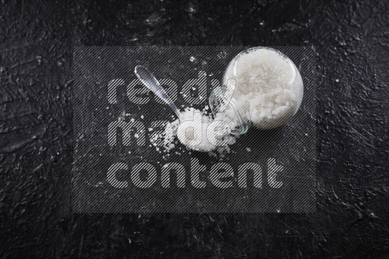 وعاء زجاجي ممتلئ بملح البحر الخشن على خلفية سوداء