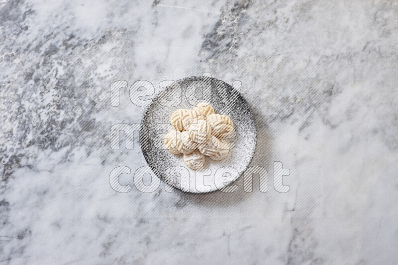 كحك في صحن فخار أسود على خلفية رخام رمادي