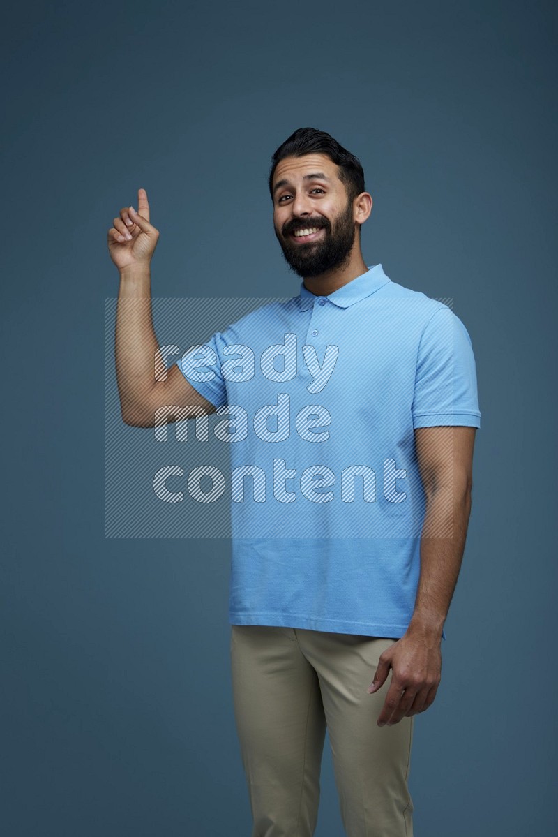 A man pointing  in a blue background wearing a Blue shirt