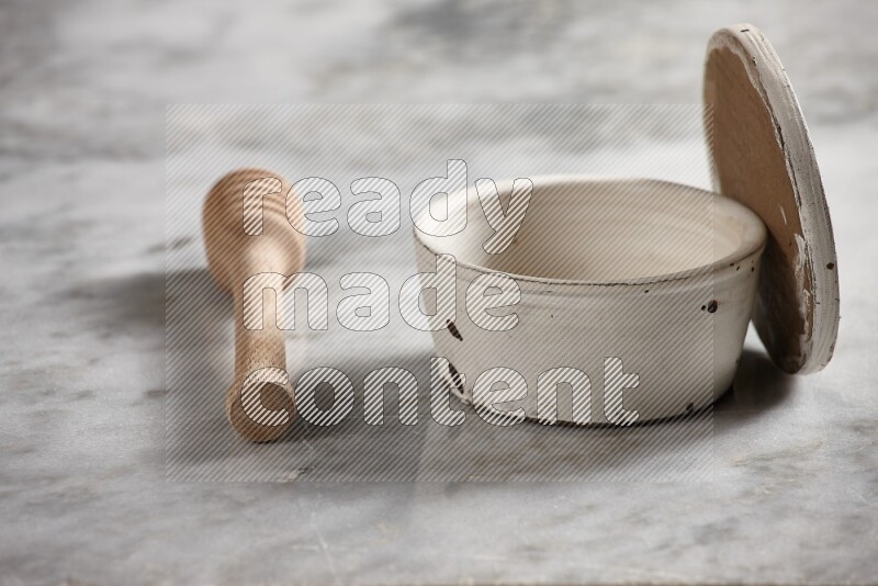White pottery bowl with wooden honey dipper on the side on grey marble background