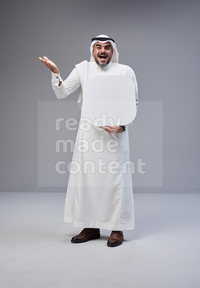 Saudi man Wearing Thob and white Shomag standing holding social media sign on Gray background