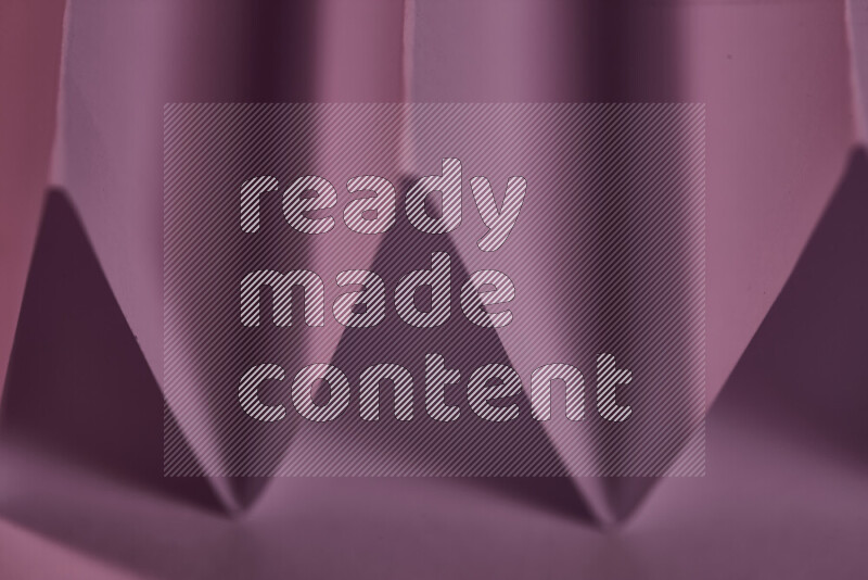 A close-up abstract image showing sharp geometric paper folds in purple gradients