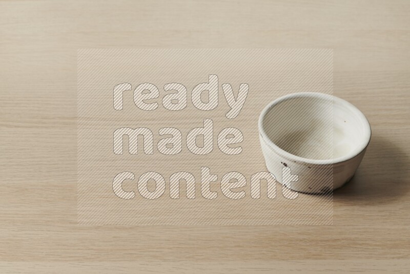 A white pottery bowl on light wooden background