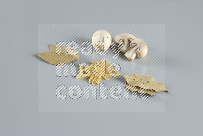 Raw pasta with different ingredients such as cherry tomatoes, garlic, onions, red chilis, black pepper, white pepper, bay laurel leaves, rosemary, cardamom and mushrooms on light blue background