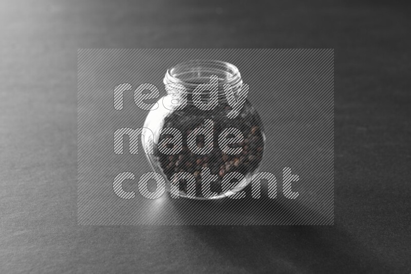 فلفل أسود في وعاء زجاجي علي خلفية سوداء