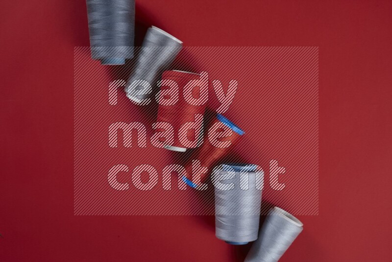 مجموعة من أدوات الخياطة والتفصيل رمادية اللون على خلفية حمراء