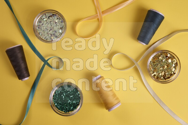 A green collection of sewing and tailoring tools arranged on a yellow background