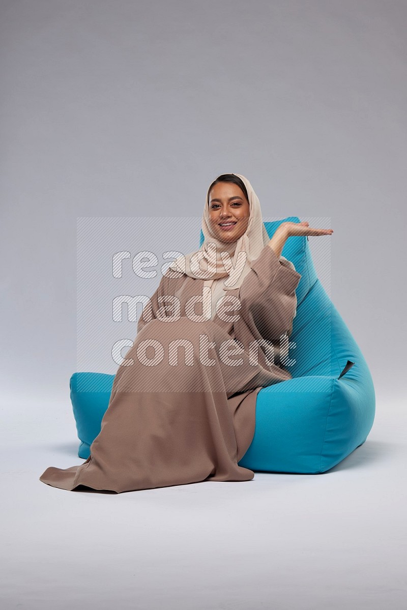 A woman sitting on a blue beanbag and interacting with the camera