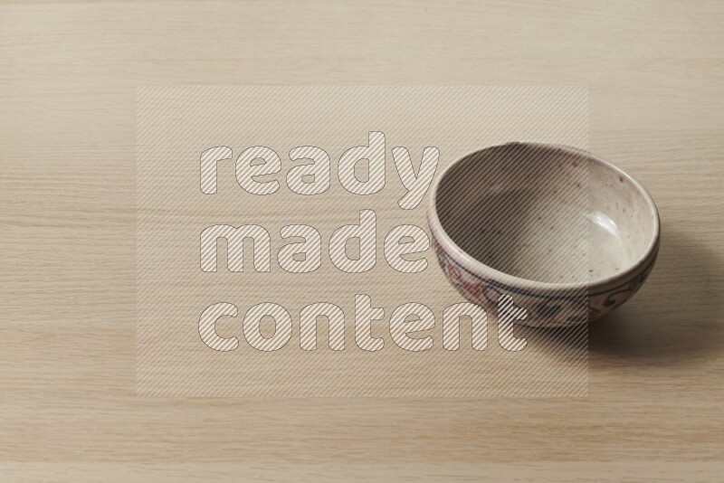 A multicolored pottery bowl on light wooden background