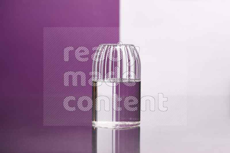 The image features a clear glassware filled with water, set against white and purple background