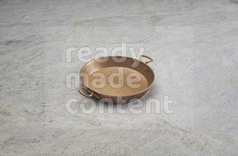 A small copper pan on grey marble background