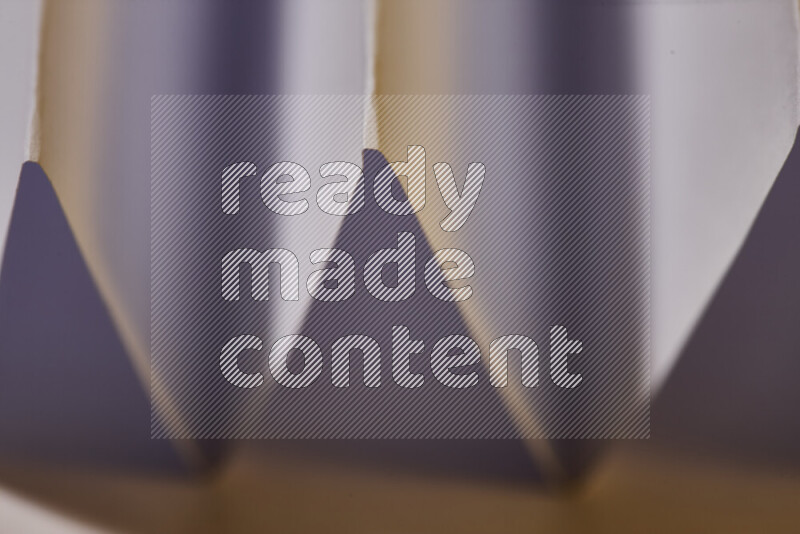 صورة مجردة مقربة تظهر طيات ورقية هندسية حادة بتدرجات اللون الأبيض مع درجات لونية دافئة